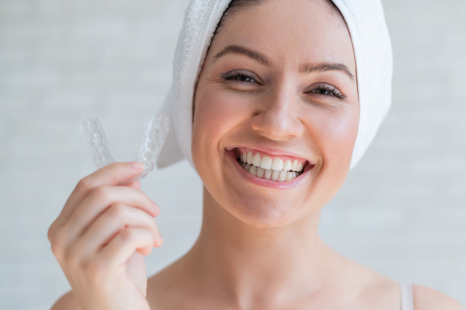 happy woman with towel wrap on head holding night guard